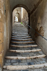 Fototapeta na wymiar Long line of stairs in alleyway with archways in Pitigliano, Italy