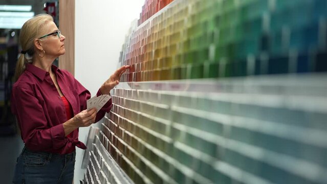 Woman looking at paint chips in a hardware store. Concept of home remodeling shopping experience.