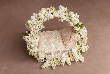 Basket with a background for a baby photo shoot.Basket for a newborn.Flower basket for a photo shoot. Basket on a beige background.White lilac.