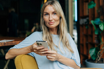 Young attractive blonde woman uses mobile phone for online messages and social media.