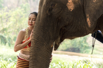 Beautiful Thai woman in traditional Thai dress standing with Asian Elephant in elephant sanctuary