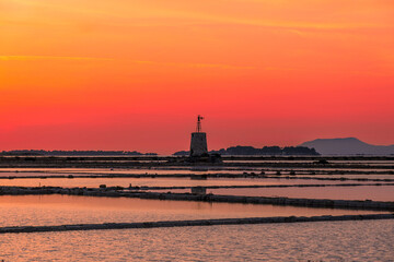 Sunset at the salt flats with the old windmill, saline dello Stagnone. Marsala, Trapani, Sicily, Italy, Europe.