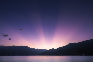 Scenery of sunlight and purple sunset sky behind mountains