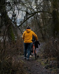 Obraz premium man walking down a trail near a forest with bikes