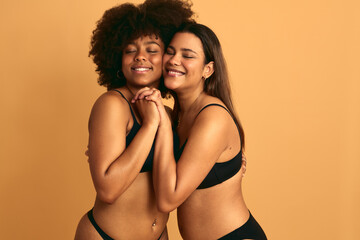 Happy diverse women in underwear holding hands together