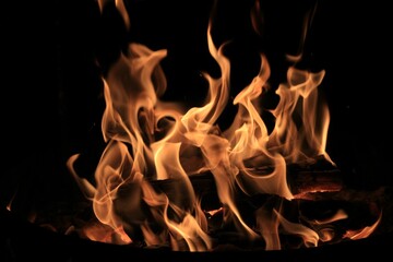 Closeup shot of wood heating in fire against a black background