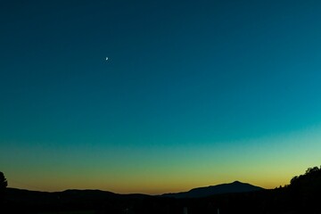 Beautiful landscape of the late sunset over the mountains with the moon just shinning