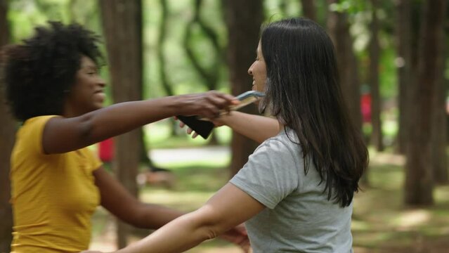Two happy young girls hug each other. Females embracing, laughing and excited. Woman friendship, walk in city park outdoors. 
