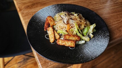 Delicious tempeh food with rice needles in the black plate