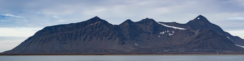 Panoramic shot of a landscape with mountains under the clouds in Svalbard, Norway