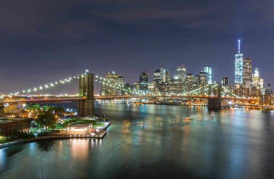 Scenic shot of the city of New York and Brooklyn bridge at night with bright beautiful city lights