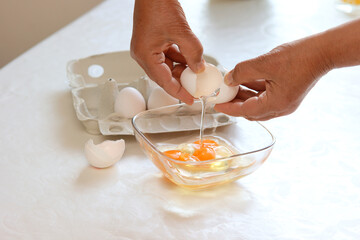 Eine Frau schlägt Eier auf in eine Schüssel