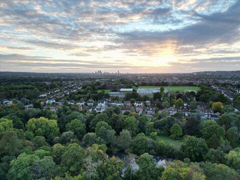 High-angle shot of a city full of buildings, green trees, fields and roads at Bromley borough.