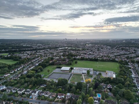 High-angle shot of a city full of buildings, green trees, fields and roads at Bromley borough.