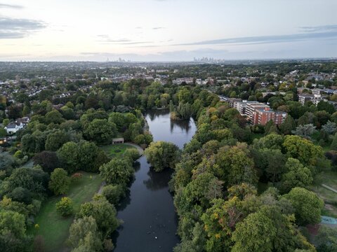 High-angle shot of a city full of buildings, green trees, fields and river at Bromley borough.