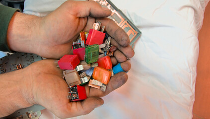 Car fuses and fuse relay box in hands. Auto electrics