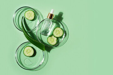 Cosmetic beauty concept with bottle serum, drops, aloe leaf and petri dish on green background