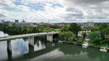 Naklejka premium Drone view of vehicles driving along the bridge connecting the riverbank on a cloudy day