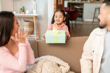 Asian Girl Giving Gift To Parents Celebrating Holiday At Home