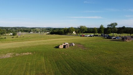 High angle shot of rocks in the middle of a green field near parked cars