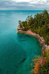 Aerial view of ocean water and rocky beach with trees
