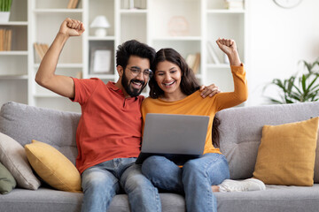 Obraz premium Online Win Joyful Young Indian Couple Celebrating Success With Laptop At Home