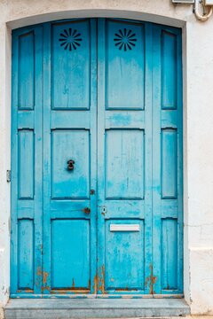Old turquoise blue house with closed wooden entrance door.