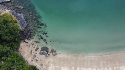 Drone view of Nui Bay beach in Thailand with rocky shore and forests in the background
