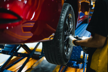 Fototapeta na wymiar Mechanic with screwdriver repairing car wheel in workshop. Changes tire spare parts.