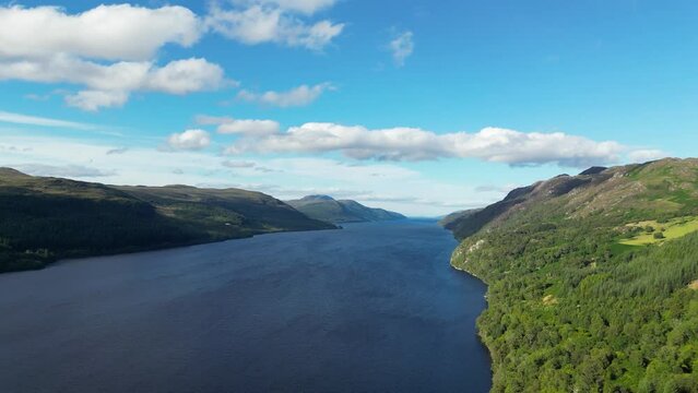 Drone flying above Loch Ness surrounded by lush green vegetation in Scotland
