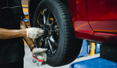 Mechanic with repairing car wheel in workshop. Hands replace tires on wheels.