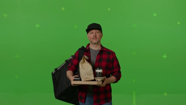 Caucasian male courier passing a box of pizza on green screen chroma key background. Man hold wireless bank payment POS terminal to process acquire credit card payment. Copy space mock up advertising