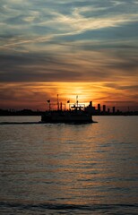 Vertical shot of a ferry in the ocean at sunset with a dramatic sky in the background, Toronto