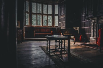Interior of an old mansion with wooden furniture and big windows in dark tones