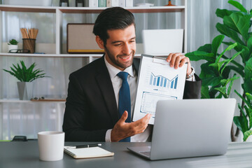 Professional businessman in black suit, present financial data or BI paper via laptop during online meeting. Remote work concept with virtual meeting presentation of effectiveness remote work. Fervent