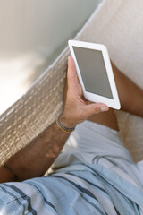 Man using a e-book while relaxing in a hammock