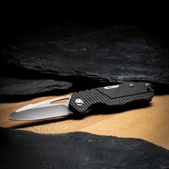 Closeup of a folding knife from dark metal stainless steal on the wooden background