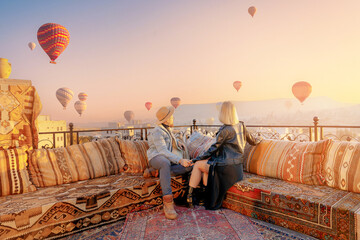 Happy lover couple man and women on rooftop of cave house enjoying of Goreme city panorama, Cappadocia Turkey travel