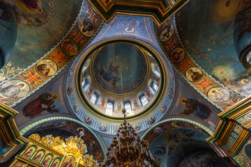 Fototapeta na wymiar Beautiful dome in an orthodox cathedral, church. Beautiful Christian murals. The sun's rays illuminate the dome beautifully. Beautiful mural with Jesus Christ. Apostles and icons.