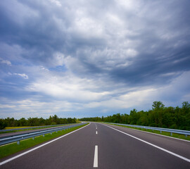 Fototapeta premium long asphalt road under dense cloudy sky