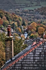 Vertical shot of Hebden Bridge market-town with old buildings surrounded by autumn trees © Point And Shoot Photos/Wirestock Creators