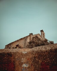 Vertical low angle shot of old castle on rocky hill on blue sky background