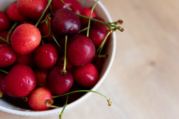 sweet cherry in a white plate on a wooden table close-up