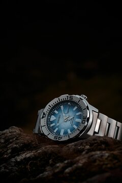 Vertical of the Seiko watch on the rock against a black background.