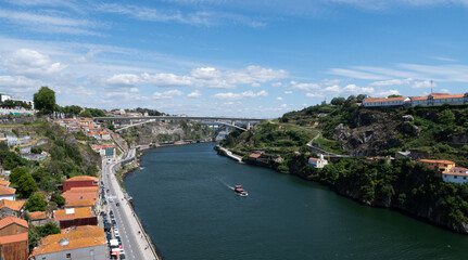 Panoramic view of the old town of Porto and the Douro river with a yacht passing through the bridge, Portugal.