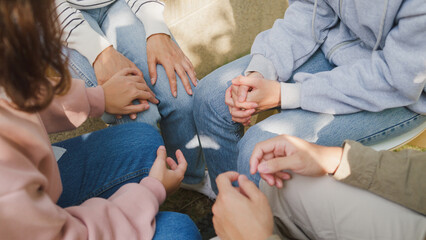 Close-up hands of diverse multiracial male and female group sit circle explain tell story sharing together in park. Support and understand at psychological therapy session, PTSD Mental health concept.