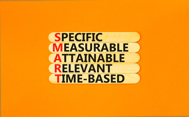 SMART symbol. Concept words SMART specific measurable attainable relevant time-based on stick. Beautiful orange background. Business SMART specific measurable attainable relevant time-based concept.