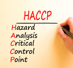 HACCP symbol. Concept words HACCP hazard analysis critical control point on white paper. Beautiful brown background. Business HACCP hazard analysis critical control point concept. Copy space.