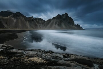 Beautiful scenery of the water in Stokksnes beach with Vestrahorn Mountains and cloudy sky, Iceland