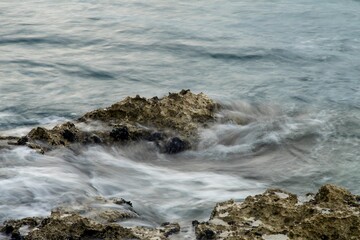 Fototapeta premium Long exposure of sea waves hitting the rocks
